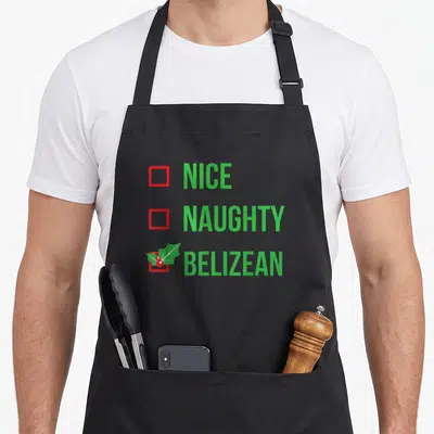 Belizean christmas apron - Green text listing Nice Naughty Belizean with red checkboxes and holly sprig over bottom box — shown on a black cotton canvas apron against a white background