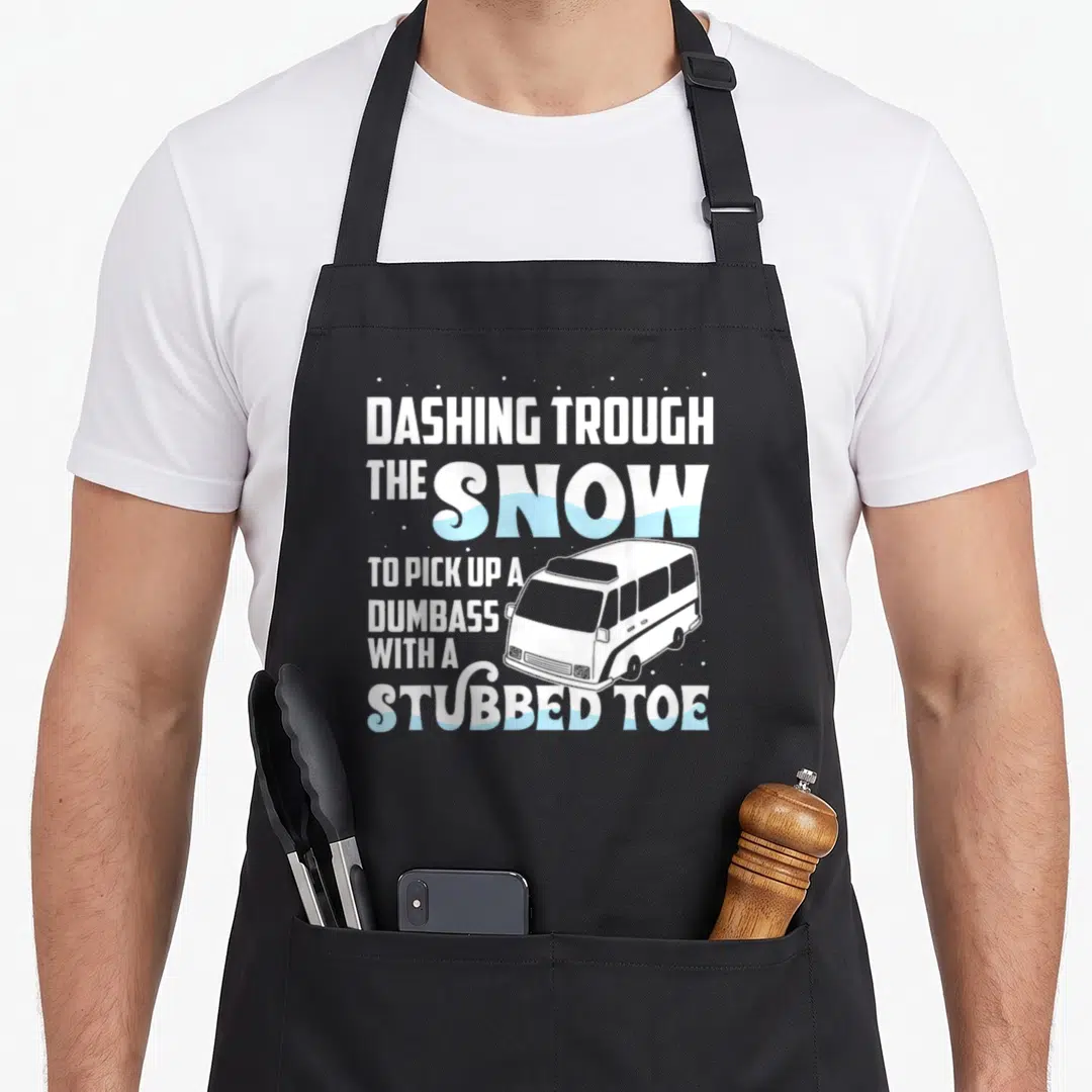 Emt christmas aprons - Stacked white and blue text reading dashing trough the snow to pick up a dumbass with a stubbed — shown on a black cotton canvas apron against a white background