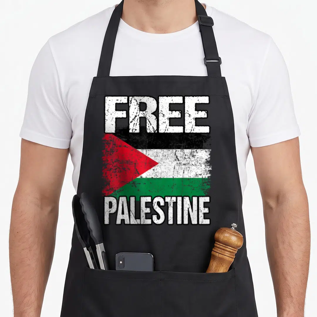 Funny free palestine apron - Distressed flag of Palestine with FREE text above and PALESTINE below in white, black — shown on a black cotton canvas apron against a white background