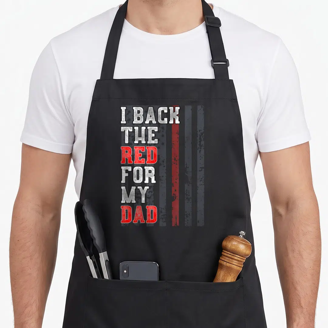 Daughter firefighter aprons - Stacked text I Back The Red For My Dad over distressed red white blue flag — shown on a black cotton canvas apron against a white background