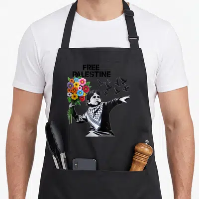Retro free palestine apron - Child holding colorful flowers and gesturing to flying birds under stacked FREE PALESTINE — shown on a black cotton canvas apron against a white background