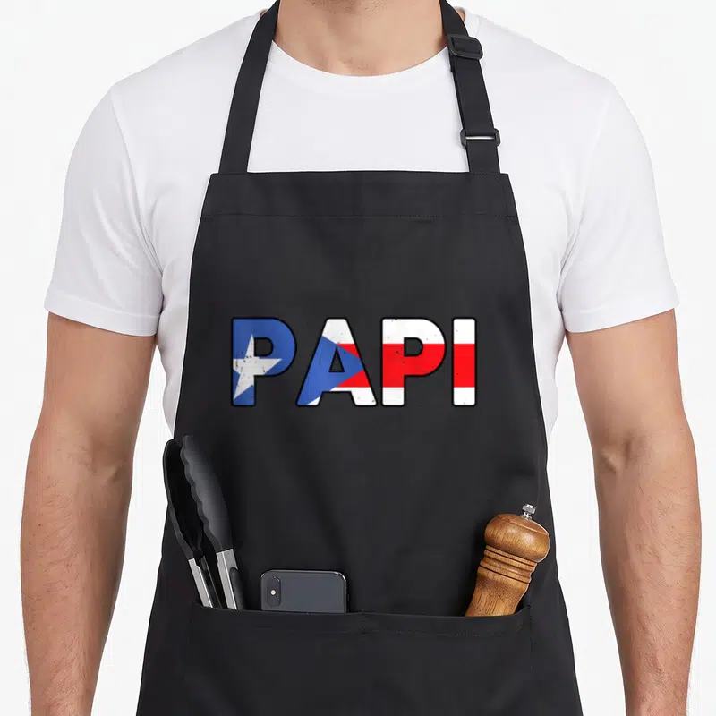 Papi rican pride apron - PAPI text filled with blue white and red Puerto Rico flag stripes — shown on a black cotton canvas apron against a white background