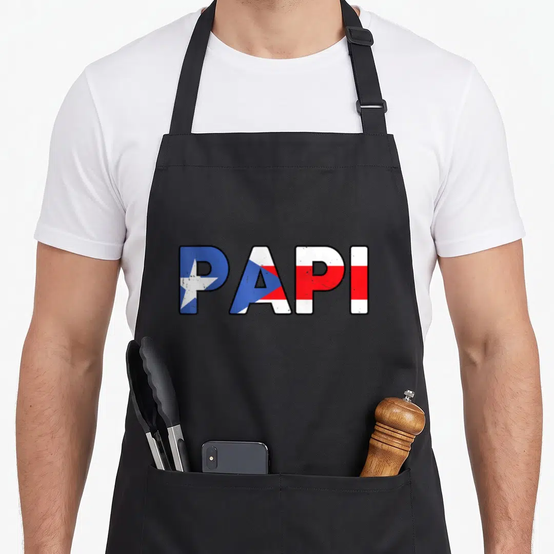Papi rican pride apron - PAPI text filled with blue white and red Puerto Rico flag stripes — shown on a black cotton canvas apron against a white background