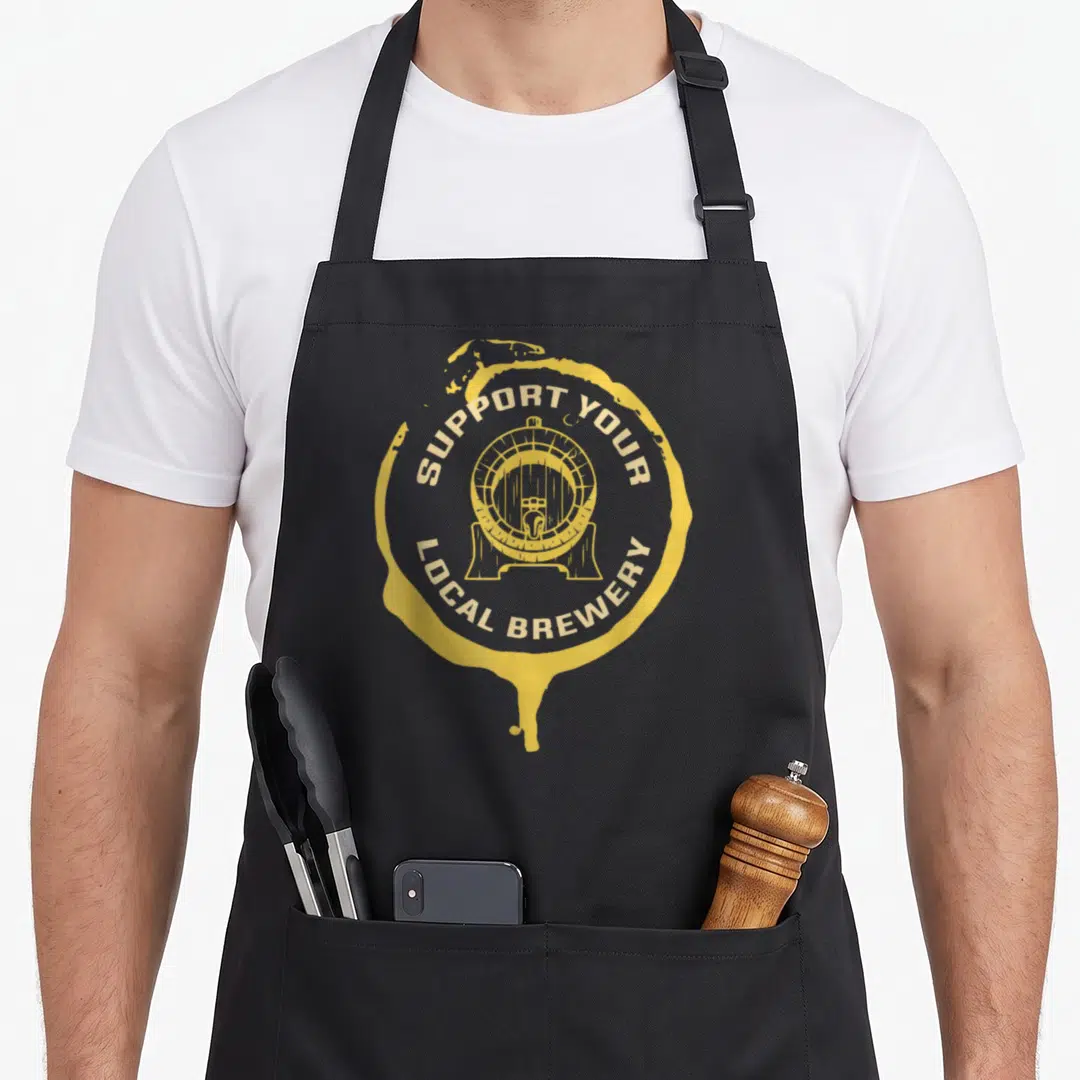 Malt beer apron - Yellow barrel inside circular splash with arched text reading SUPPORT YOUR LOCAL BREWERY — shown on a black cotton canvas apron against a white background