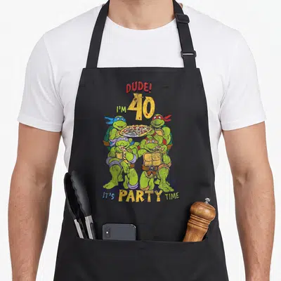 Pizza 40th birthday apron - Four cartoon turtles holding pizza under DUDE I'M 40 IT'S PARTY TIME text — shown on a black cotton canvas apron against a white background