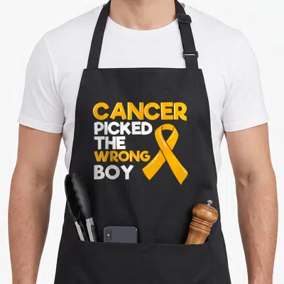 Pediatrician ribbon apron - Orange awareness ribbon next to stacked CANCER PICKED THE WRONG BOY text in orange and white — shown on a black cotton canvas apron against a white background