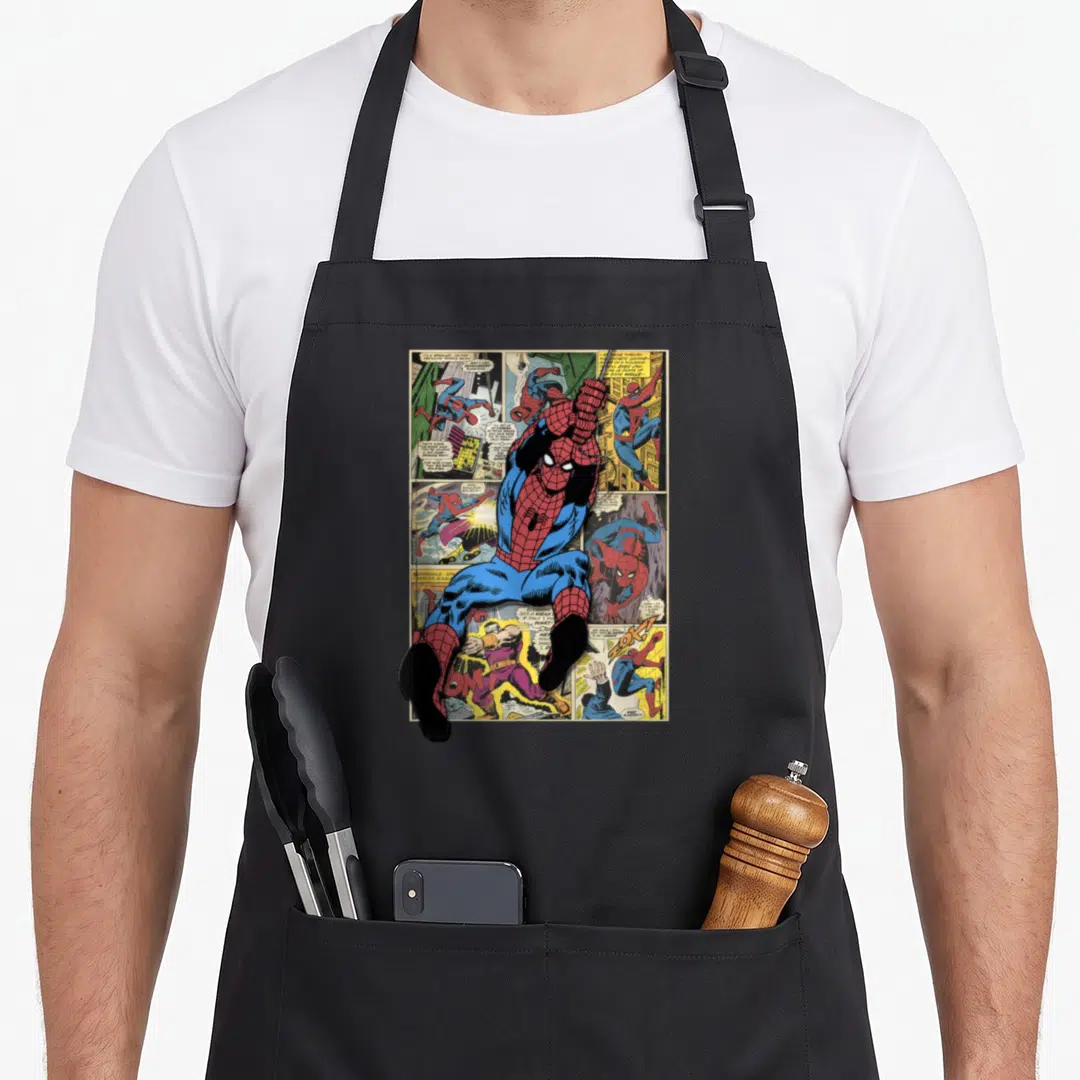 Night crawler apron - Spider-Man figure over vintage comic panels in red blue and yellow cartoon style — shown on a black cotton canvas apron against a white background