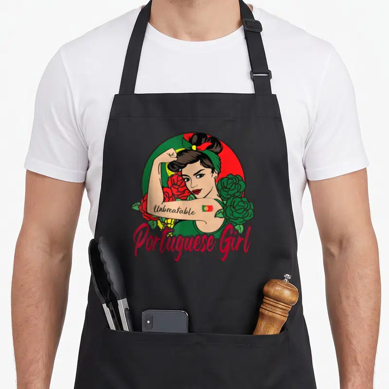 Funny flag portuguese apron - Cartoon woman flexing arm with Unbreakable text and red green roses over Portuguese flag — shown on a black cotton canvas apron against a white background