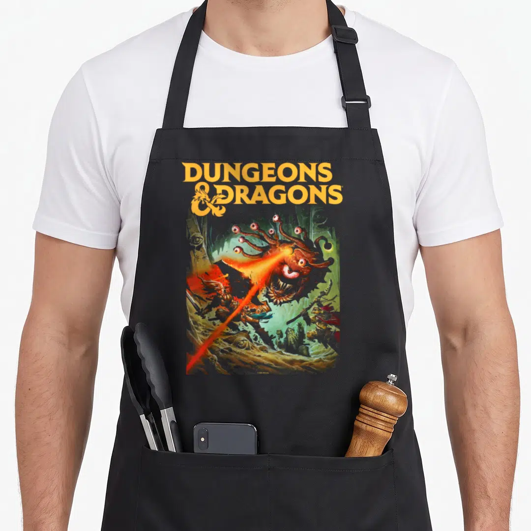 Strike dungeon apron - Orange D&D text above a brown beholder firing a red beam at cave monsters in green and grey tones — shown on a black cotton canvas apron against a white background