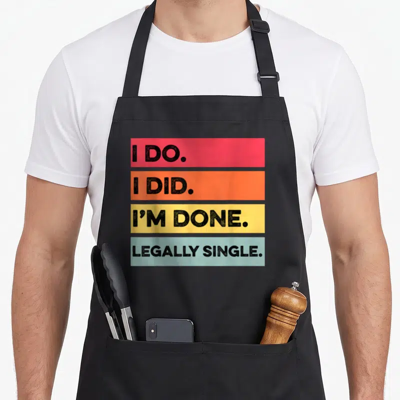 Legally divorce party apron - Four stacked colored bars reading I DO, I DID, I'M DONE, and LEGALLY SINGLE in black text — shown on a black cotton canvas apron against a white background