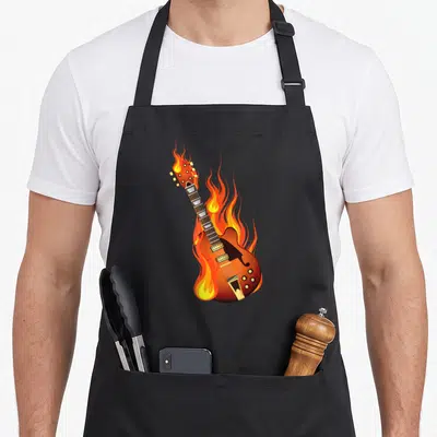 Burning heavy apron - Diagonal electric guitar engulfed in cartoon flames colored brown orange yellow and red — shown on a black cotton canvas apron against a white background