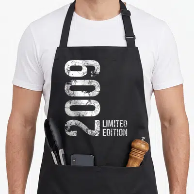 Limited 17th birthday apron - Vertical distressed white 6002 numbers next to Limited Edition text — shown on a black cotton canvas apron against a white background