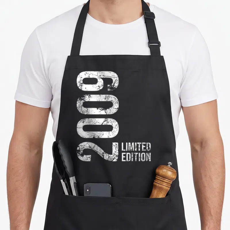 Limited 17th birthday apron - Vertical distressed white 6002 numbers next to Limited Edition text — shown on a black cotton canvas apron against a white background