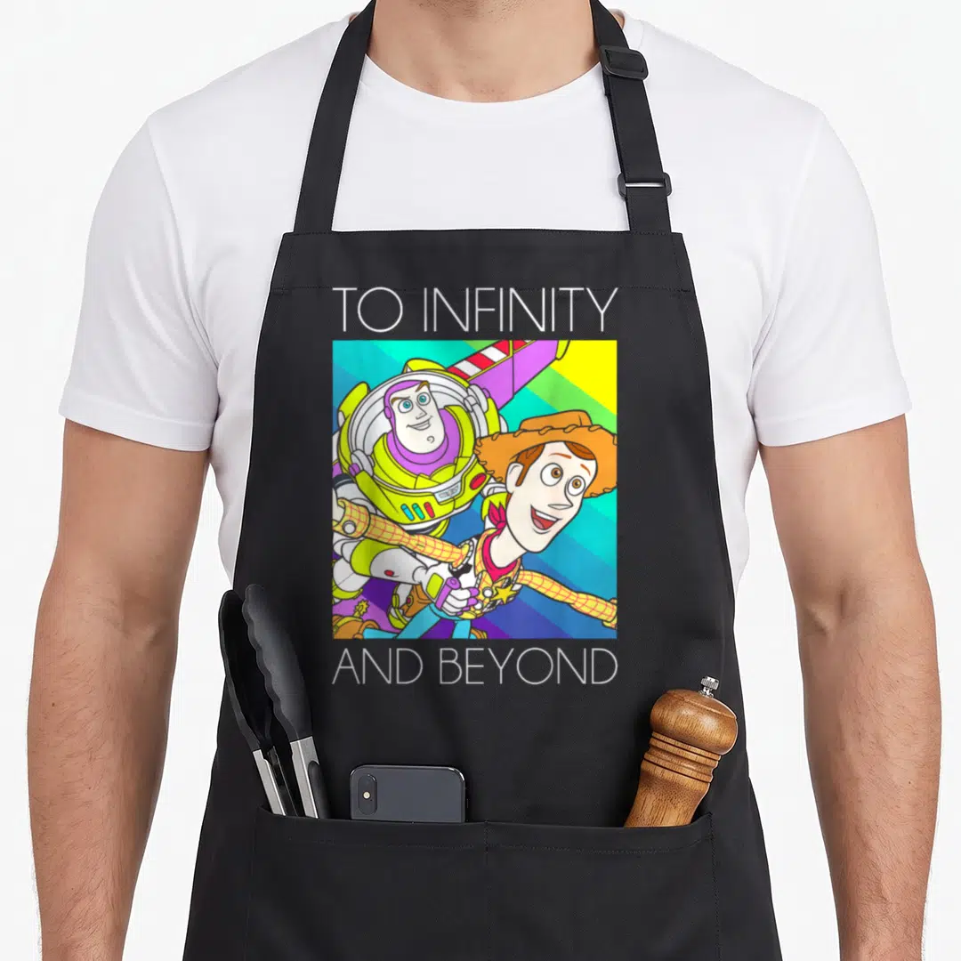 Buzz infinity apron - Buzz Lightyear and Woody cartoon graphic with TO INFINITY AND BEYOND text — shown on a black cotton canvas apron against a white background