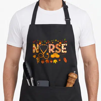 Health thanksgiving apron - NURSE text with stethoscope U surrounded by orange and brown autumn leaves pumpkins — shown on a black cotton canvas apron against a white background