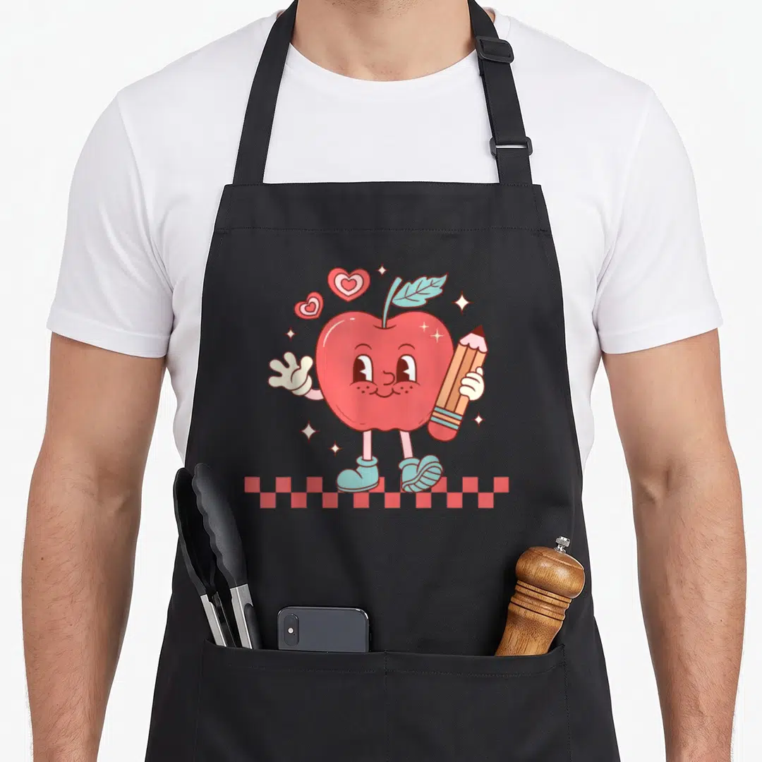 Checkered teacher apron - Retro cartoon apple holding pencil on checkerboard floor with hearts and stars — shown on a black cotton canvas apron against a white background