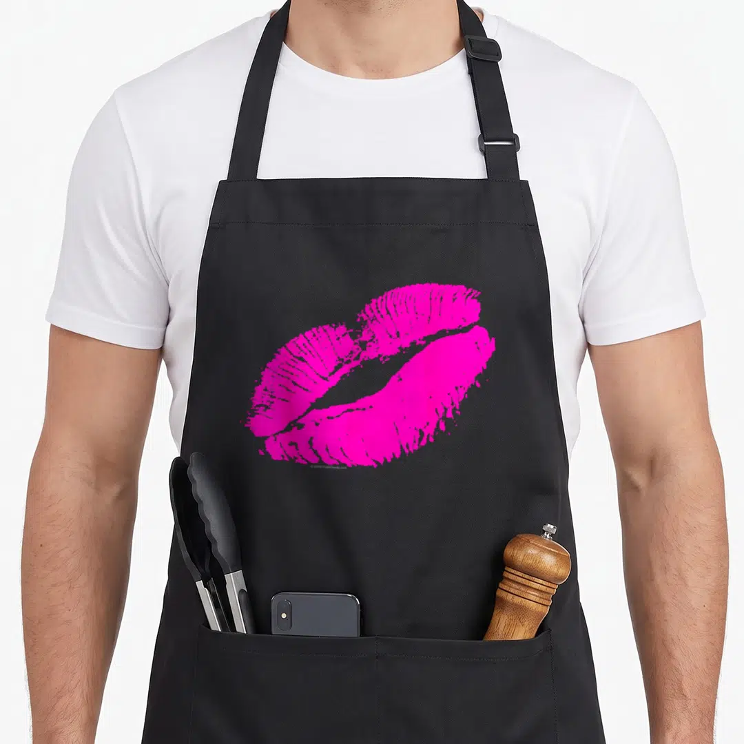 Lip 80s apron - Cartoon pink lipstick kiss mark print on black apron front panel — shown on a black cotton canvas apron against a white background