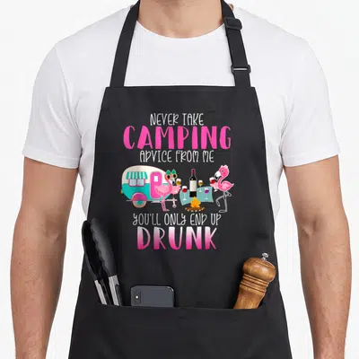 Advice youll camping apron - Pink flamingos with wine glasses next to a turquoise camper trailer under white and pink — shown on a black cotton canvas apron against a white background