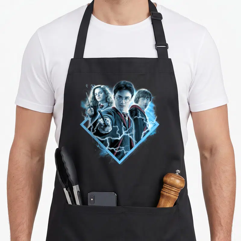 Granger potter apron - Harry, Hermione, and Ron in blue diamond with lightning bolts photo art — shown on a black cotton canvas apron against a white background