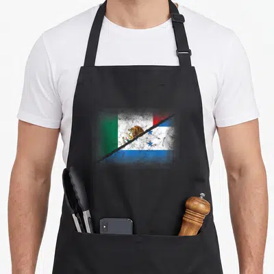 Honduras mexico apron - Two flags merged by a jagged tear in green white red and blue distressed print — shown on a black cotton canvas apron against a white background