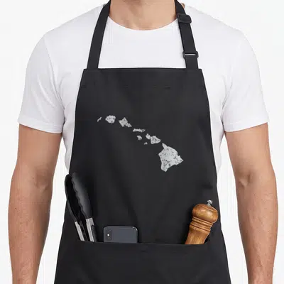 Hawaiian kitchen island apron - White minimalist silhouette of the Hawaiian island chain centered on grey background — shown on a black cotton canvas apron against a white background