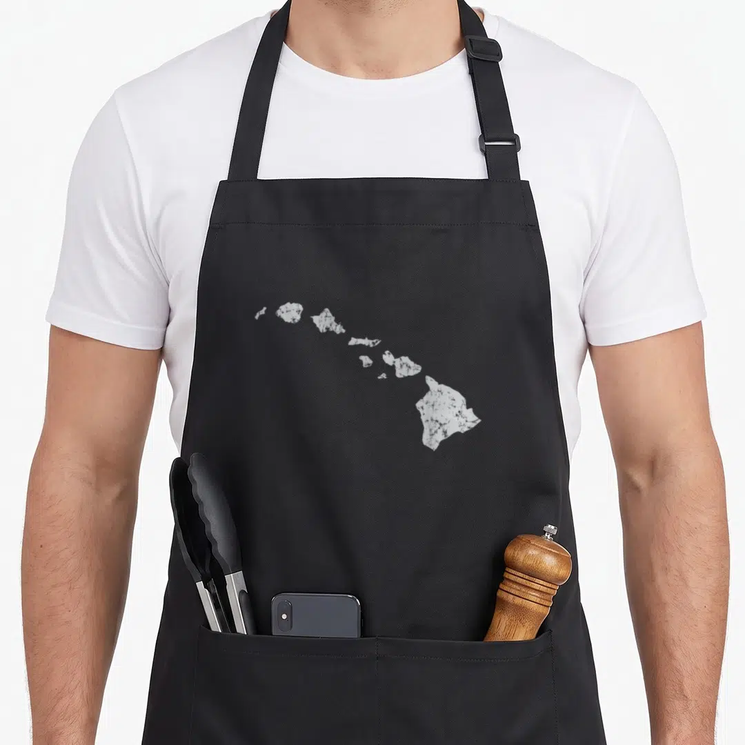 Hawaiian kitchen island apron - White minimalist silhouette of the Hawaiian island chain centered on grey background — shown on a black cotton canvas apron against a white background