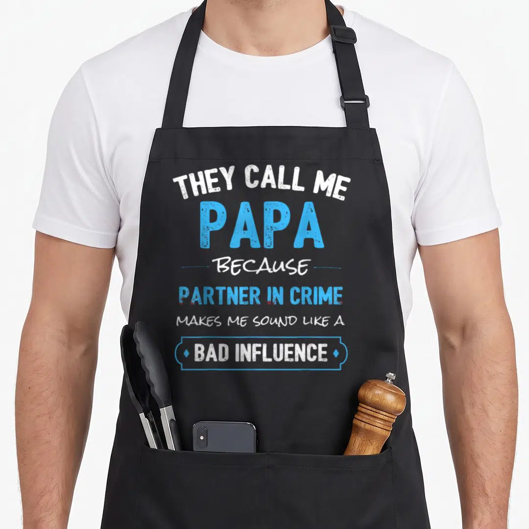 Papa grandpa apron - White and blue typography reading They Call Me Papa Because Partner In Crime Makes Me Sound Like — shown on a black cotton canvas apron against a white background