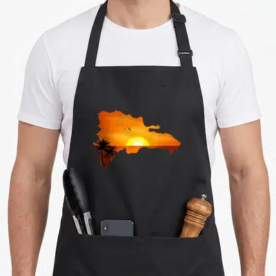 Domrep santo domingo apron - Silhouette of Dominican Republic map filled with orange sunset, yellow sun, black palm — shown on a black cotton canvas apron against a white background