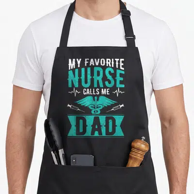 Call daughter nurses apron - My Favorite Nurse Calls Me Dad with teal caduceus and two syringes on distressed banner — shown on a black cotton canvas apron against a white background