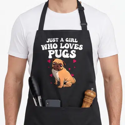 Pug pet dog apron - Just A Girl Who Loves Pugs text above seated tan cartoon pug with pink hearts — shown on a black cotton canvas apron against a white background