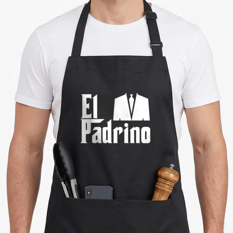 Padrino communion apron - White El Padrino text beside a minimalist suit and tie silhouette — shown on a black cotton canvas apron against a white background