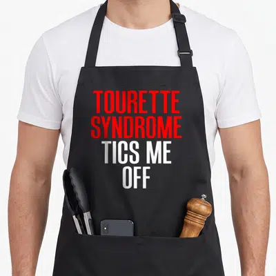 Tic tourette awareness apron - Red and white stacked text reading TOURETTE SYNDROME TICS ME OFF — shown on a black cotton canvas apron against a white background