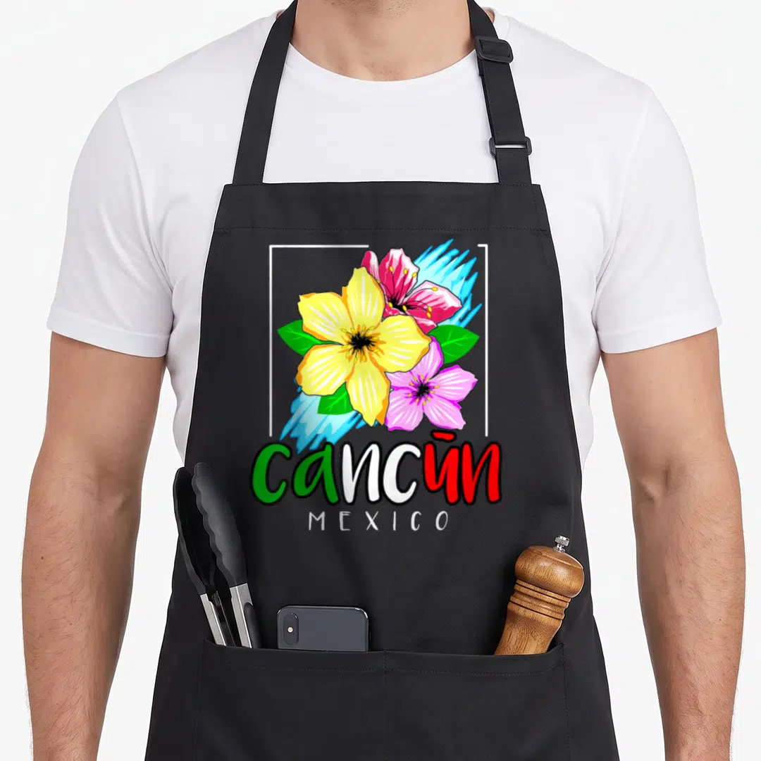 Cancun spring aprons - Cartoon flowers in yellow pink red with cancun MEXICO text and white frame — shown on a black cotton canvas apron against a white background