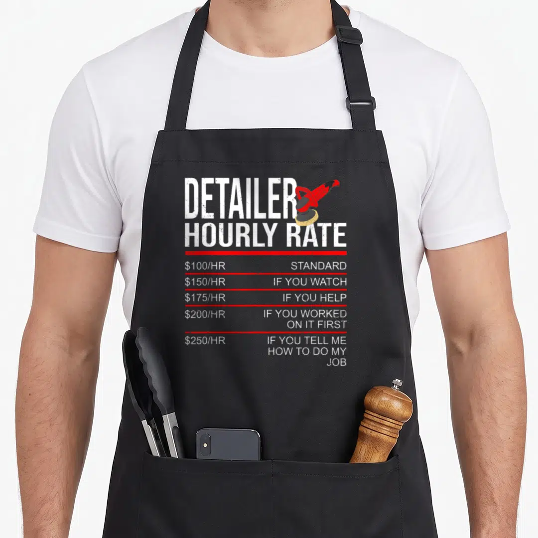 Hourly auto apron - Distressed white text listing hourly rates separated by red lines next to a red buffer — shown on a black cotton canvas apron against a white background