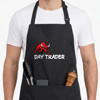 Broker stock aprons - Red cartoon bull charging above white distressed text reading DAY TRADER — shown on a black cotton canvas apron against a white background