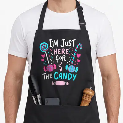 Candy lollipop halloween apron - Stacked text I'M JUST HERE for THE CANDY with lollipop candy cane and hearts in white — shown on a black cotton canvas apron against a white background