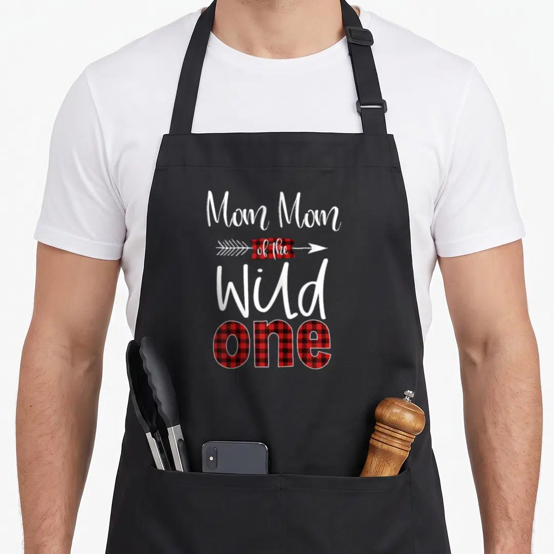 1st buffalo plaid apron - Mom Mom of the Wild ONE text with red black plaid arrow and arrowhead — shown on a black cotton canvas apron against a white background