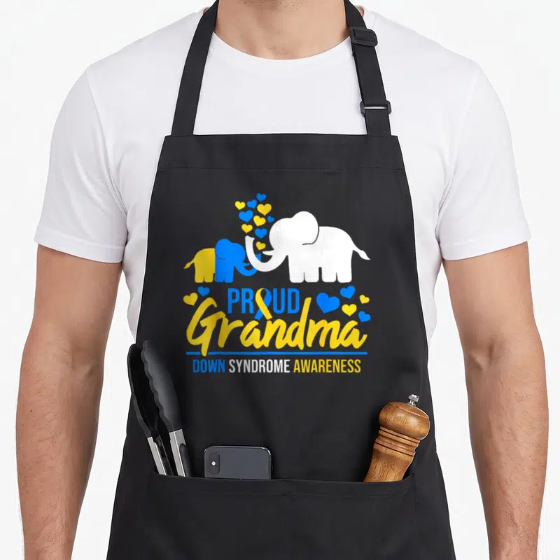 Syndrome grandma apron - Elephant silhouettes and stacked text Proud Grandma Down Syndrome Awareness in blue yellow — shown on a black cotton canvas apron against a white background