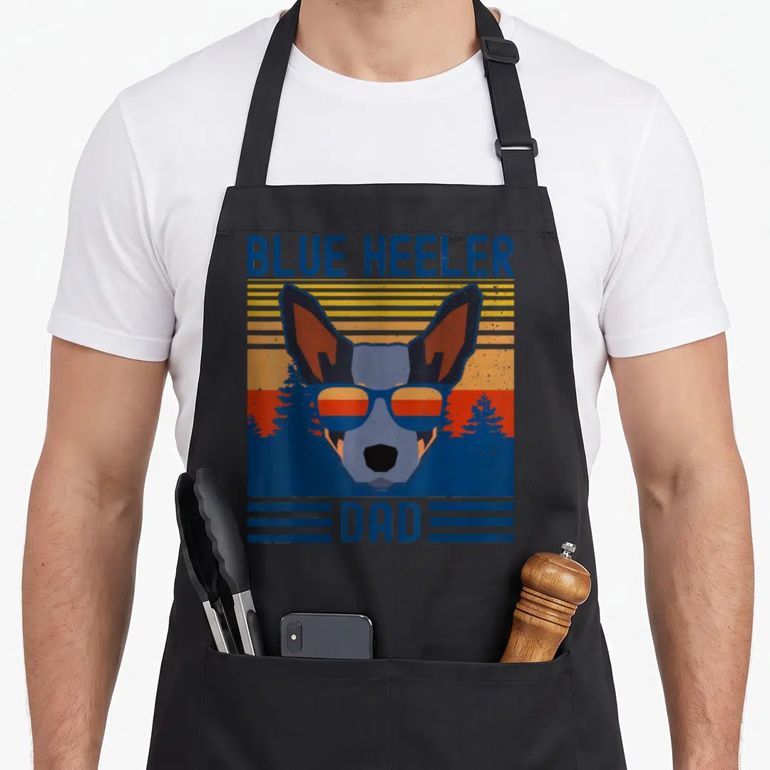 Australian cattle dog apron - Retro Blue Heeler dog head with sunglasses and sunset background — shown on a black cotton canvas apron against a white background