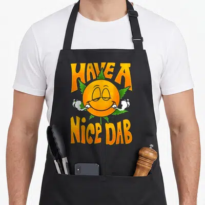 Weed dab apron - Orange smiley face with white smoke and green leaf under HAVE A NICE DAB text — shown on a black cotton canvas apron against a white background
