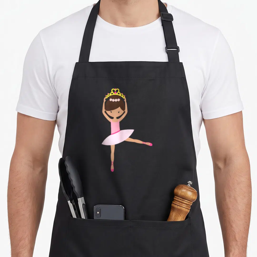 Modern unique apron - Cartoon girl in pink tutu holding yellow crown and wearing flower headband — shown on a black cotton canvas apron against a white background