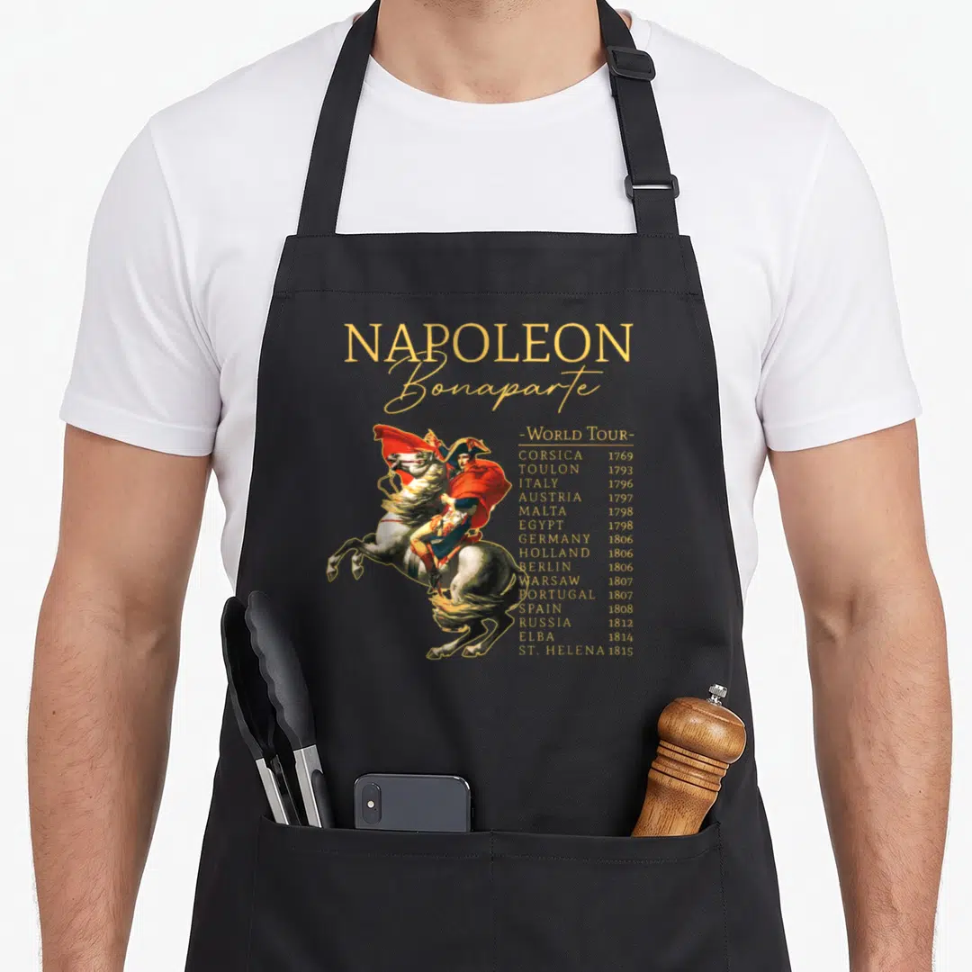 Tour military apron - Napoleon Bonaparte World Tour list with gold text and equestrian painting — shown on a black cotton canvas apron against a white background