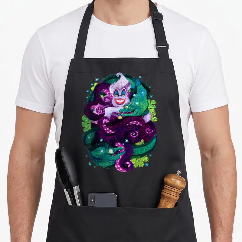 Ursula witch apron - Watercolor white-haired monster with purple tentacles, green snakes, and blue crystals — shown on a black cotton canvas apron against a white background