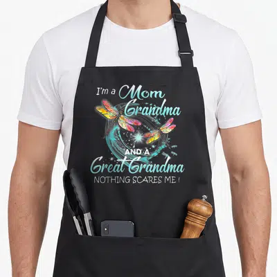 Scare grandma apron - Stacked text I'm a Mom Grandma Great Grandma with two multicolored dragonflies over blue swirls — shown on a black cotton canvas apron against a white background