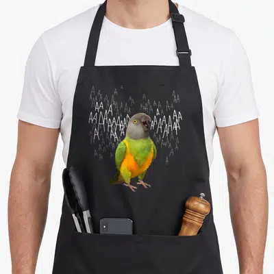 Screaming senegal parrot apron - Realistic green and grey parrot with open beak surrounded by scattered white letter — shown on a black cotton canvas apron against a white background