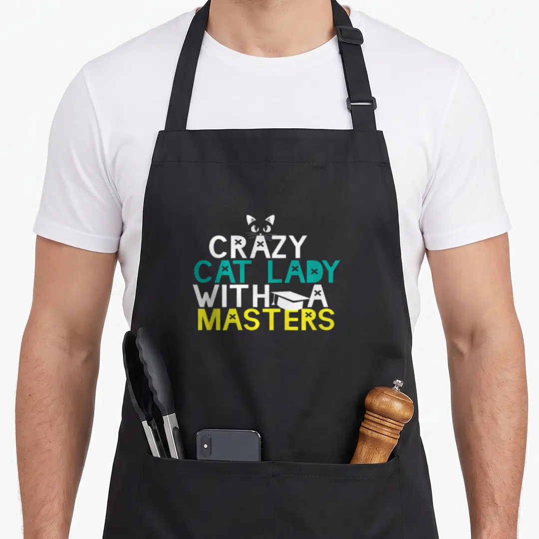 Master crazy cat lady apron - CRAZY CAT LADY WITH A MASTERS text with cat head and grad cap in white teal yellow — shown on a black cotton canvas apron against a white background