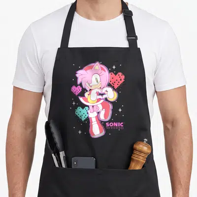 Valentine rose apron - Amy Rose pixel art making heart shape with pink and cyan hearts and Sonic logo — shown on a black cotton canvas apron against a white background
