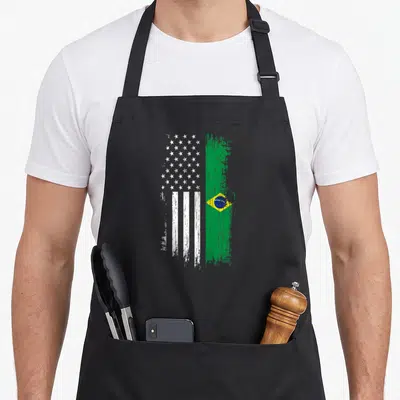 Brazilian pride american flag apron - Vertical split USA and Brazil flag design with distressed paint strokes in white — shown on a black cotton canvas apron against a white background