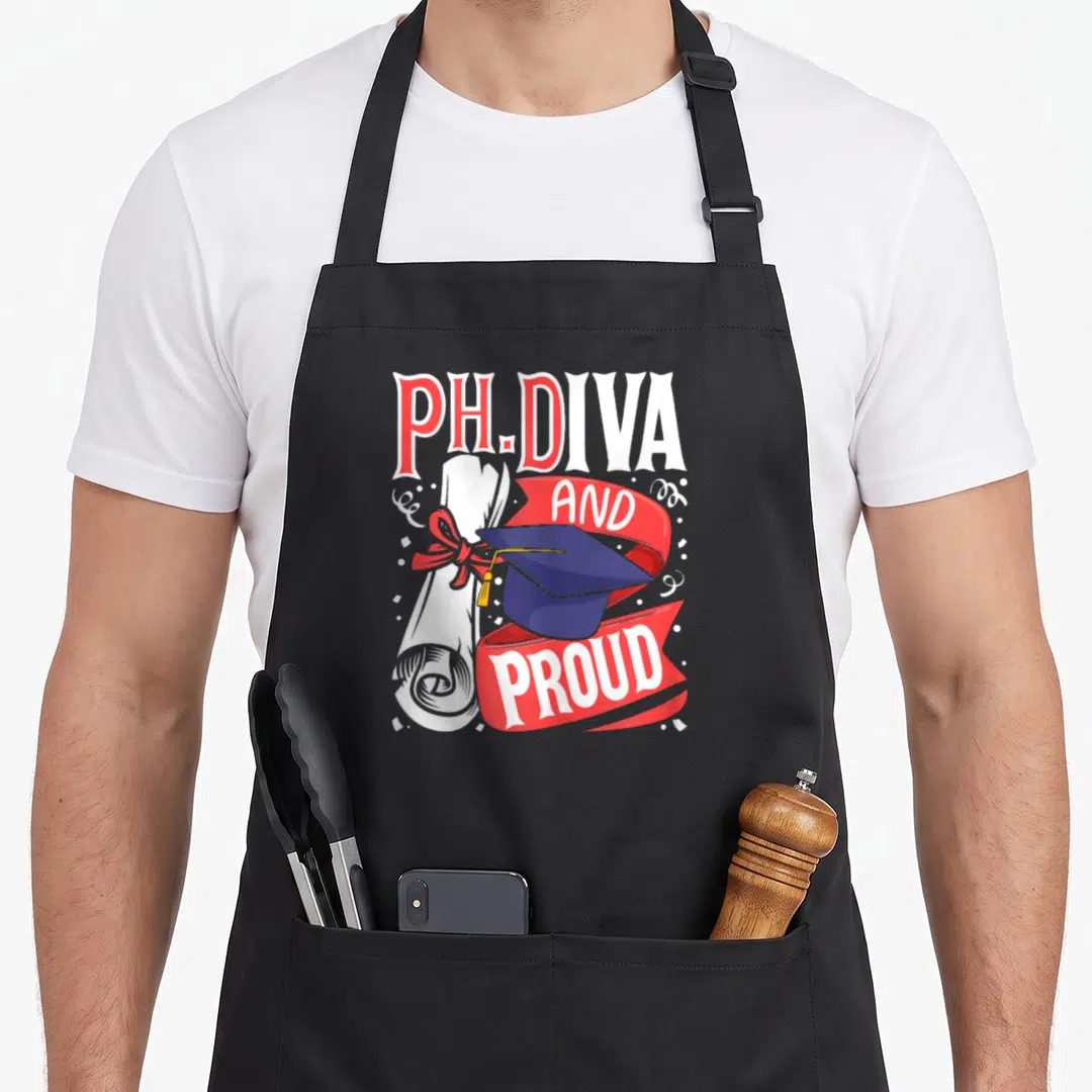 Diva dissertation apron - PH.DIVA text with blue graduation cap, white diploma, and red ribbon reading AND PROUD — shown on a black cotton canvas apron against a white background