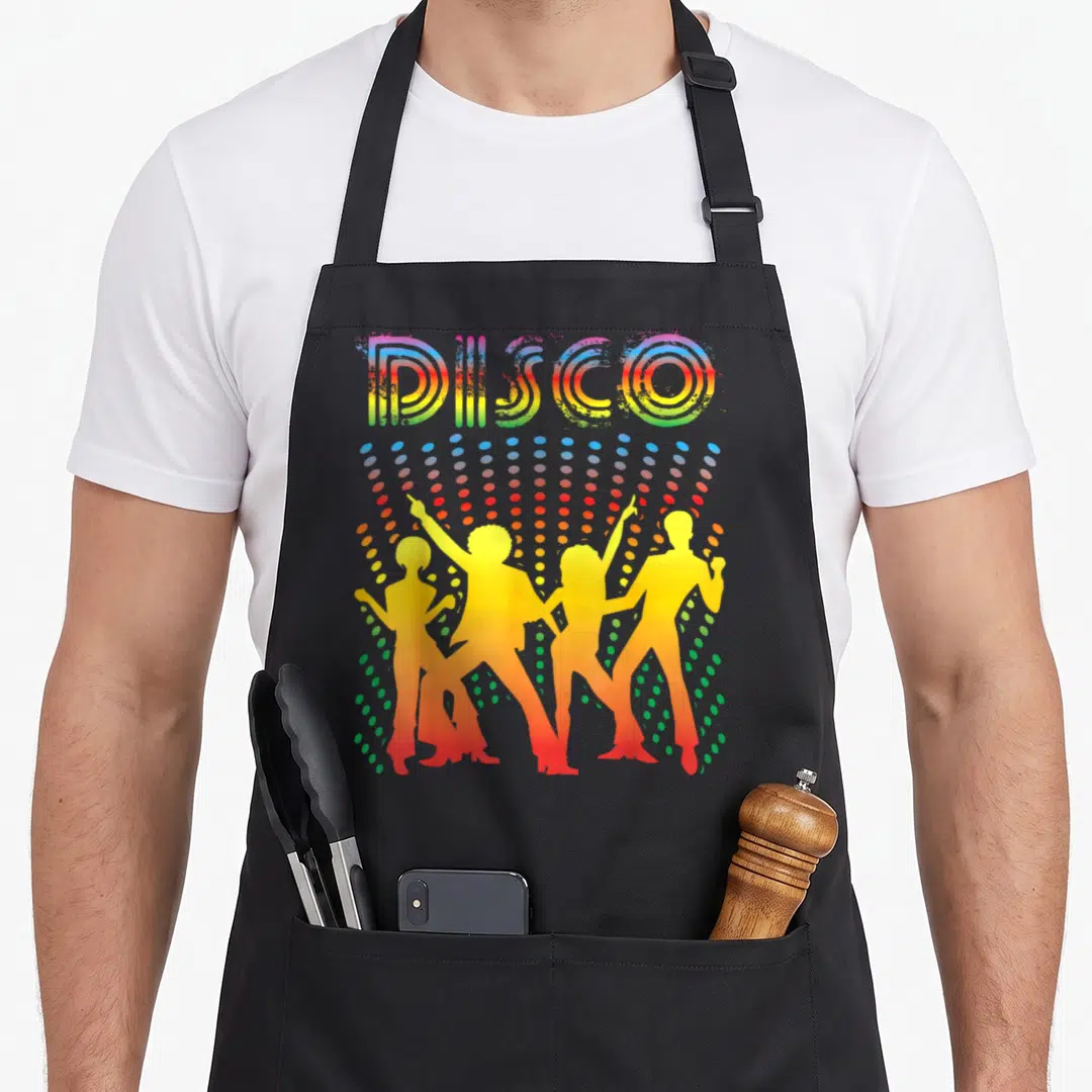 Dancing disco apron - Retro DISCO lettering above four yellow dancer silhouettes and multicolored dot pattern — shown on a black cotton canvas apron against a white background